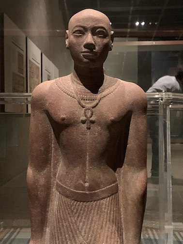 25th Dynasty Prince Horemakhet statue. He wears an ankh necklace around his neck. He has no hair. His lips are thinner than Osorkon, Iuput, and Taharka. Statue in the Nubian Museum.